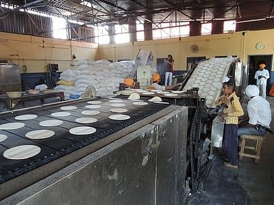 Grote keuken met lopende band waarop ronde broden worden gebakken